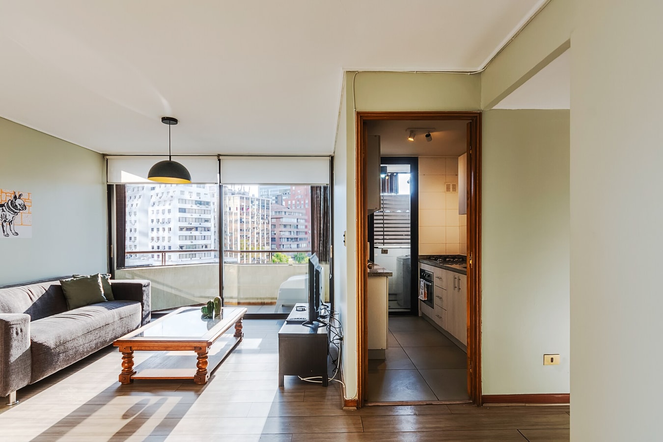 Living con sofá, mesa de centro de madera y balcón con vista a la ciudad.
