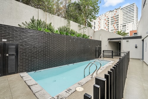 Piscina del edificio, vista general con reja perimetral y edificios de fondo