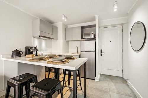 Cocina con barra desayunador, banquetas y acceso a la puerta de entrada