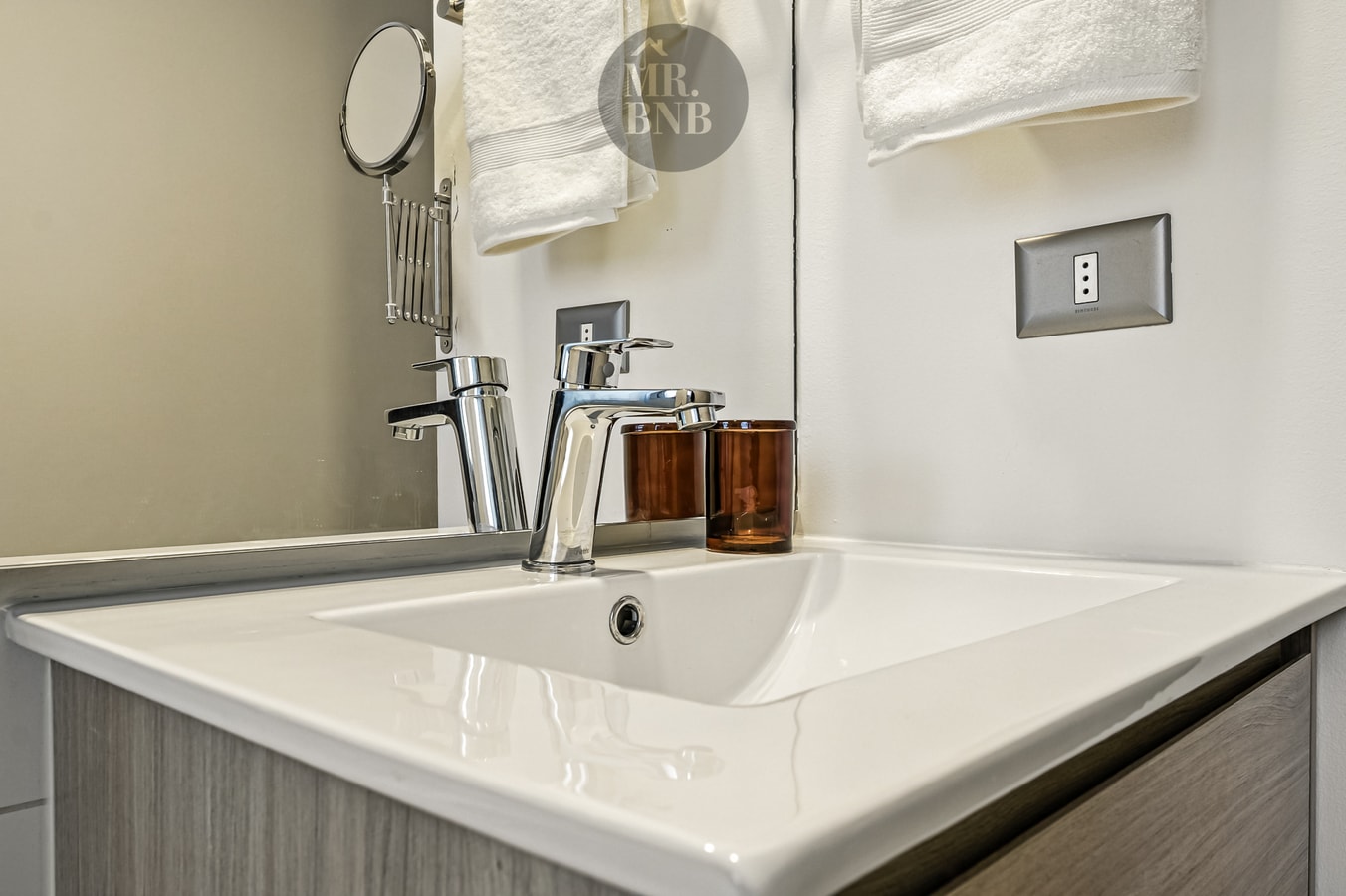 Detalle del lavamanos del baño, con grifería, espejo y dispensadores de jabón