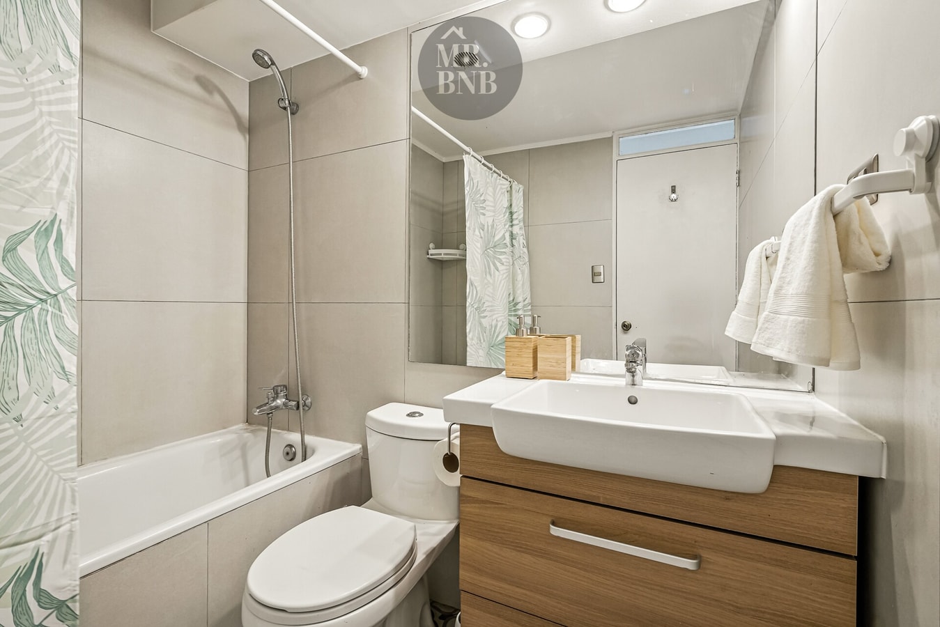 Baño con tina, ducha telefónica y mueble de madera con lavamanos
