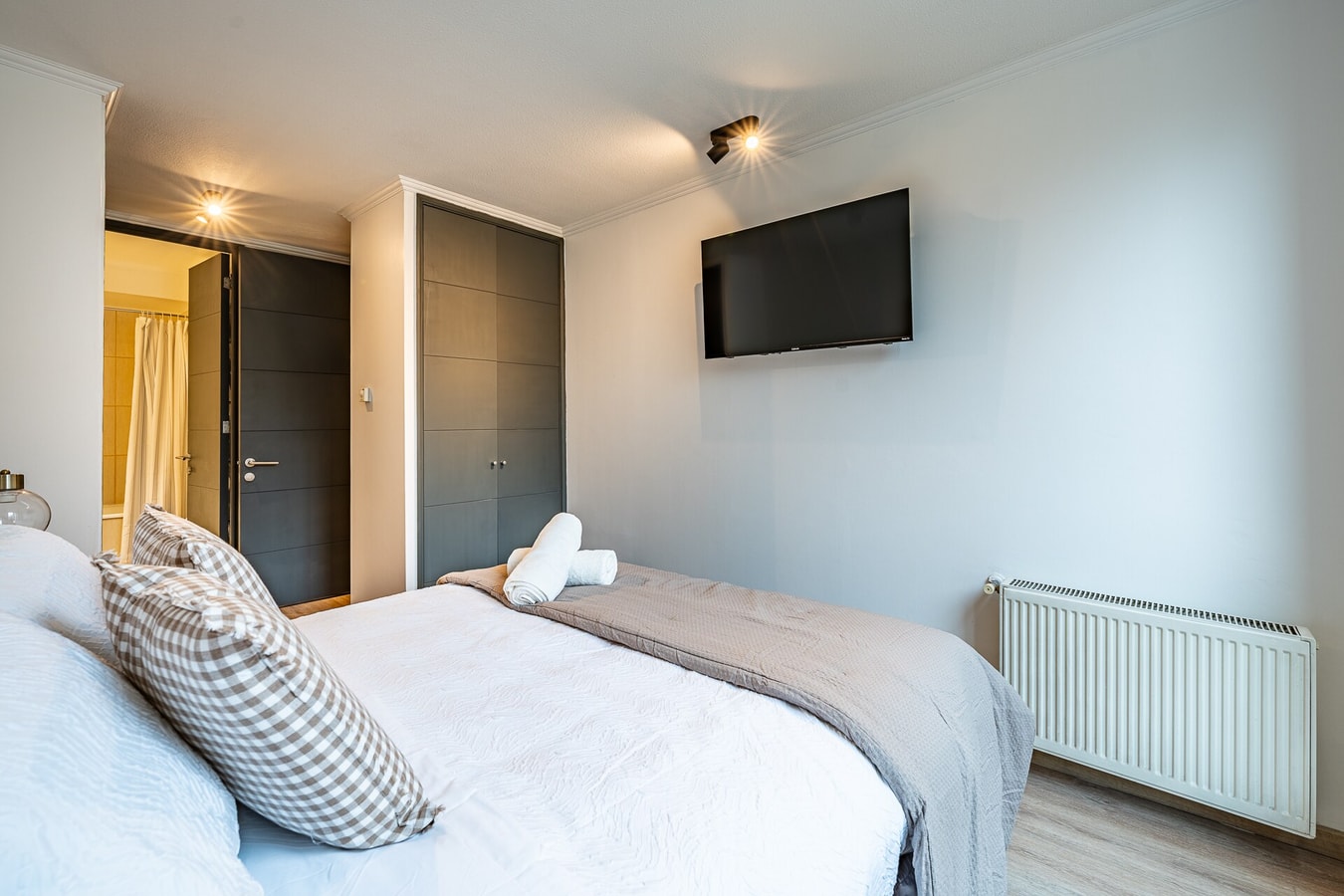 Dormitorio con cama, televisor en la pared y radiador