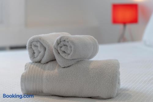 Detalle de toallas blancas enrolladas sobre la cama, con lámpara roja de fondo