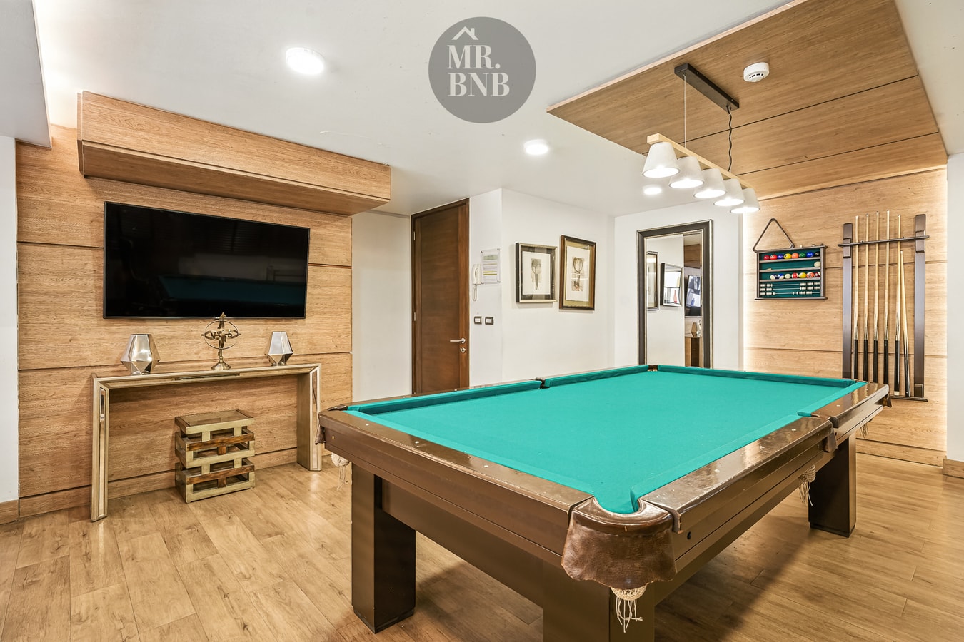 Salón con mesa de pool, cuadros y muebles de madera.