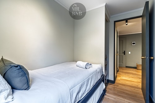 Dormitorio con cama, veladores y pasillo hacia otras habitaciones