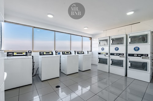 Sala de lavandería del edificio con varias lavadoras y secadoras apiladas
