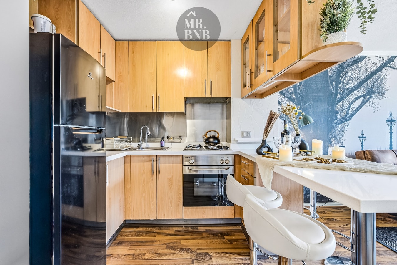 Cocina de madera con horno, cocina a gas y barra alta con sillas.