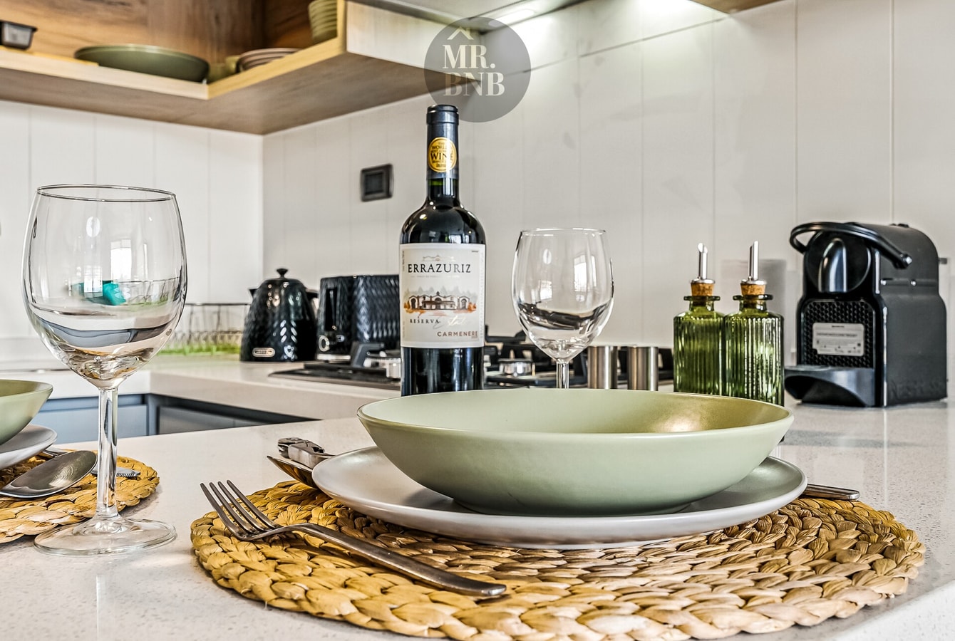 Mesón de cocina con servicio de bienvenida: vino, copas y plato servido.
