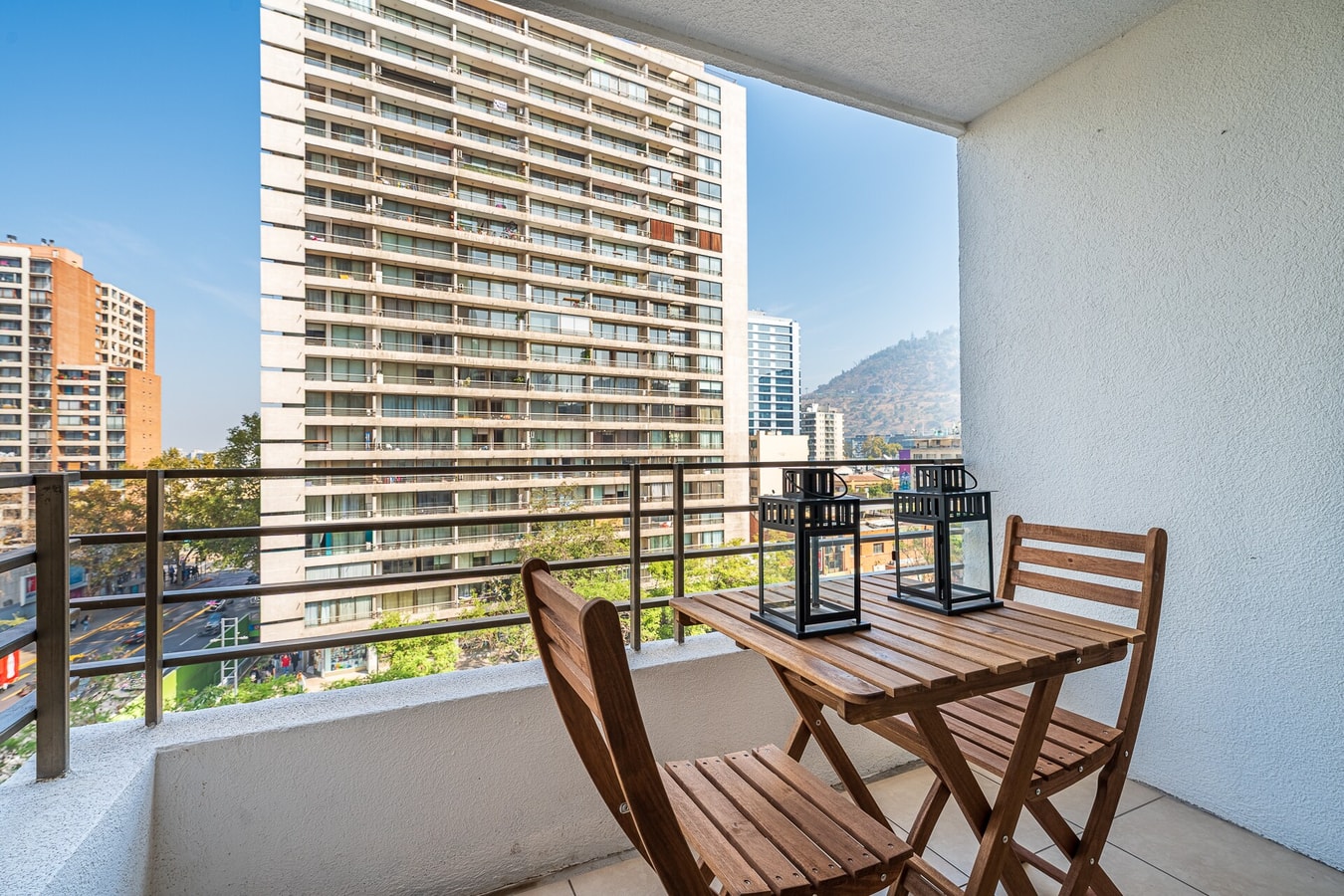Terraza privada con mesa y dos sillas, vista a edificios y al cerro