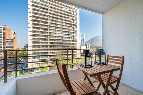 Terraza privada con mesa y dos sillas, vista a edificios y al cerro