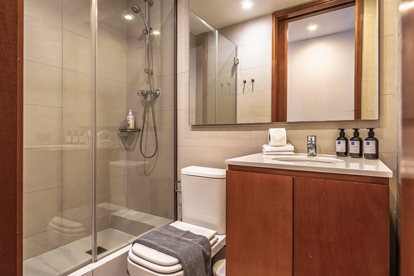 Baño con ducha de vidrio, tina, lavamanos y set de amenities.