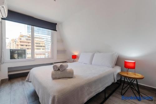 Dormitorio con cama, toallas dobladas sobre el cubrecama y veladores con lámparas rojas