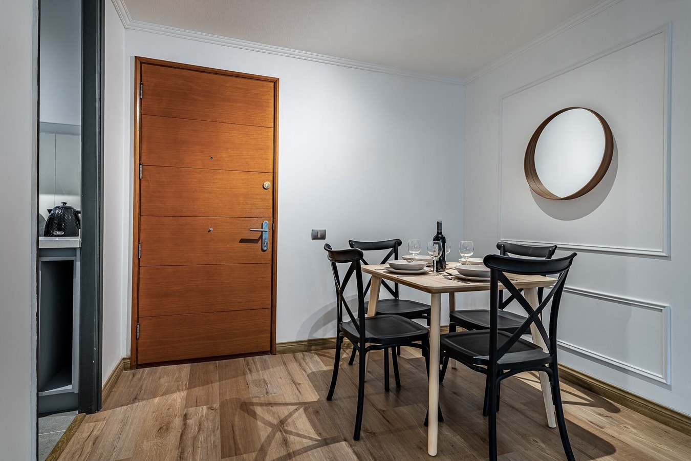 Comedor junto a la puerta de acceso, con mesa, sillas y espejo redondo