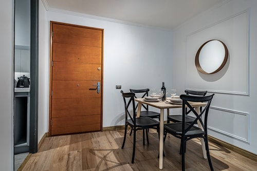 Comedor junto a la puerta de acceso, con mesa, sillas y espejo redondo