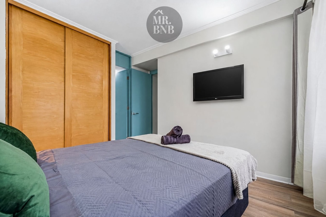 Dormitorio con cama, closet y TV en la pared