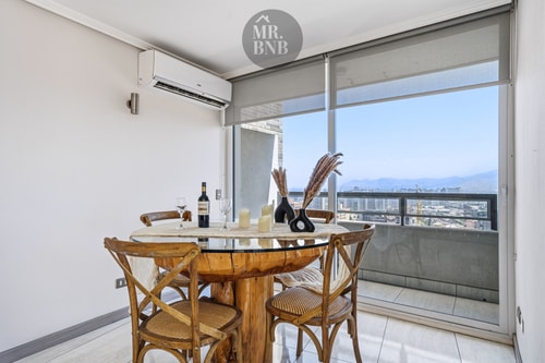Comedor junto a ventanal con puerta corredera, mesa redonda y botella de vino