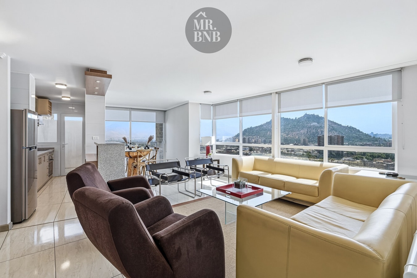 Living amplio con sofás crema y café, mesa de centro y ventanales con vista al cerro
