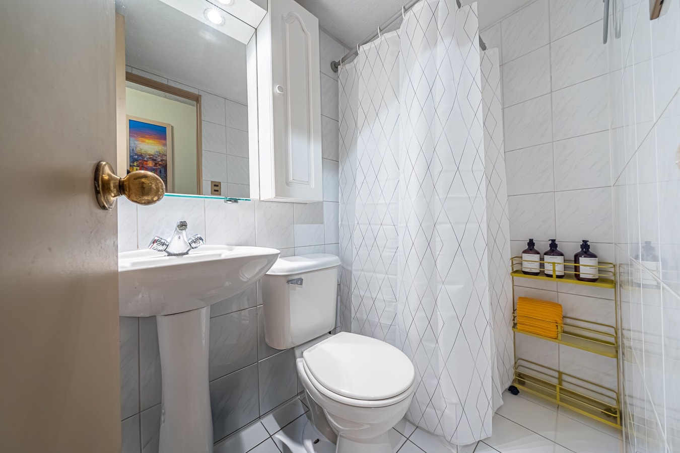 Baño con lavamanos, inodoro y cortina de ducha estampada.