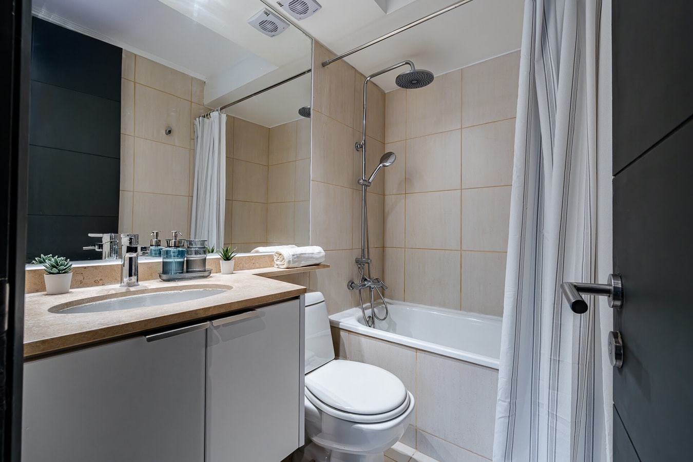 Baño con tina, cortina, mueble vanitorio e inodoro