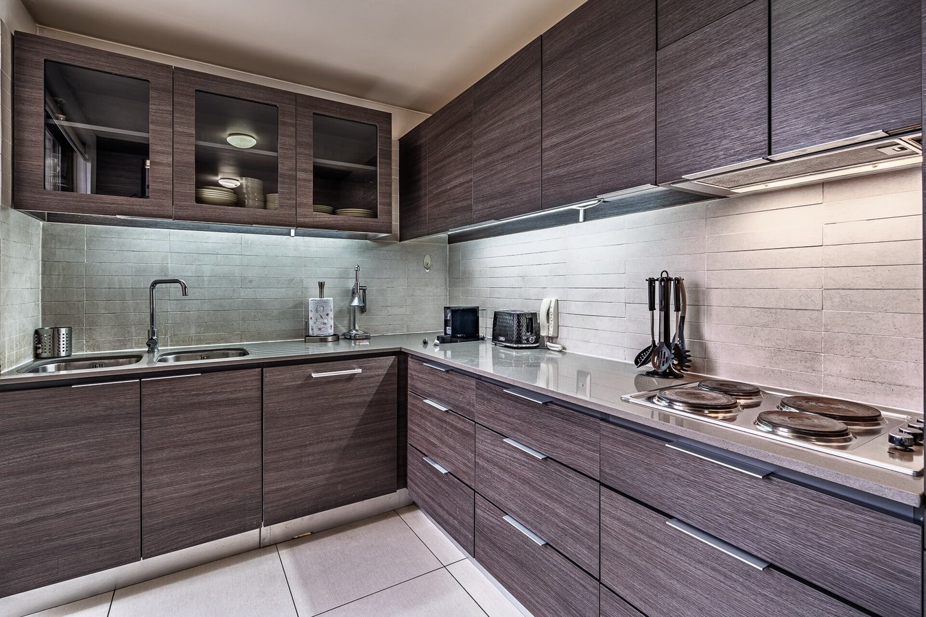 Cocina equipada con encimera eléctrica, extractor y utensilios sobre la mesada.