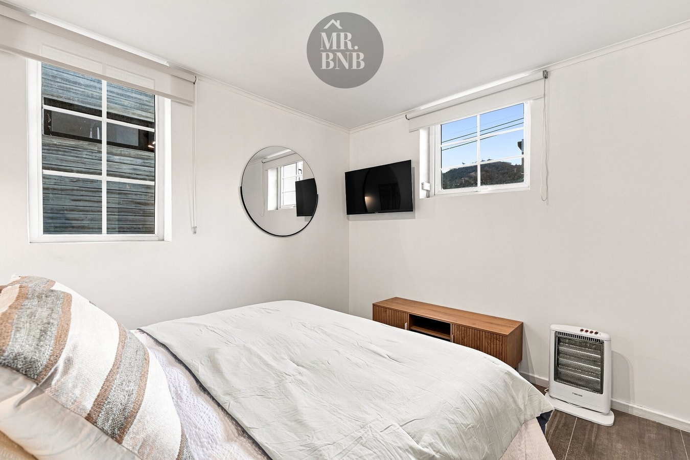 Dormitorio con TV, cama y ventana redonda