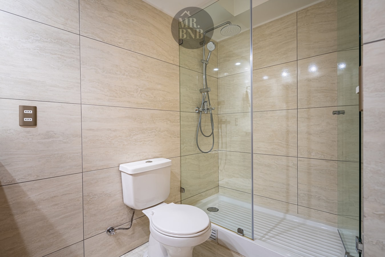 Ducha con puerta de vidrio y muro de cerámica clara