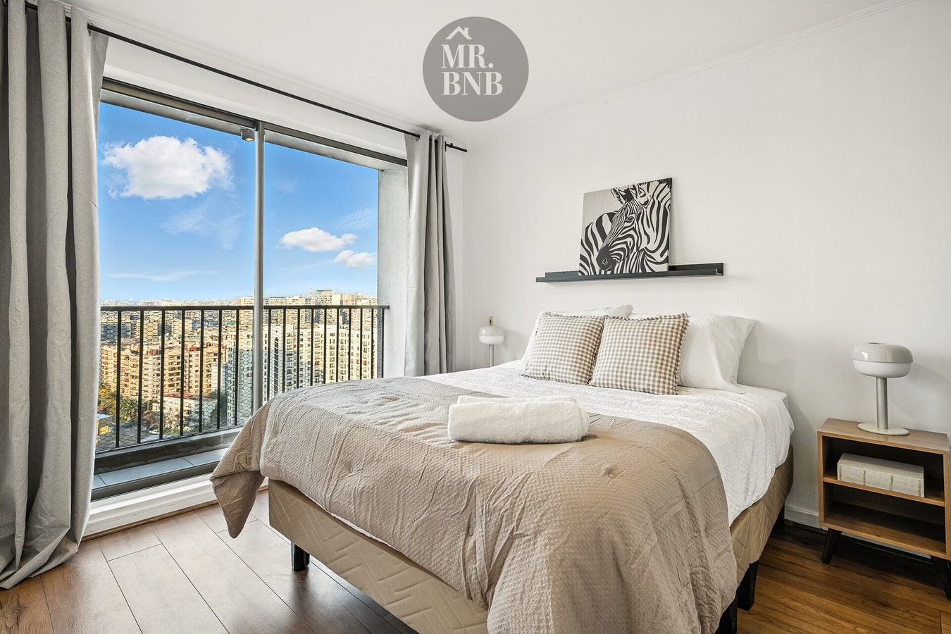 Dormitorio con cama doble, ventanal amplio y vista a la ciudad