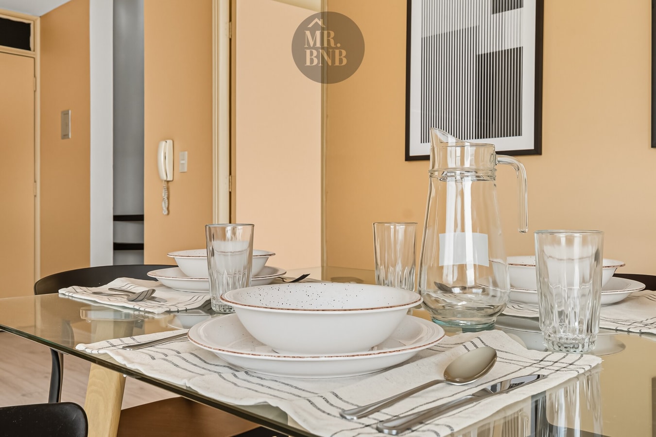 Detalle de mesa de comedor puesta con vajilla, jarra de agua y cubiertos