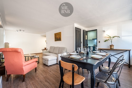 Living comedor con sillón naranjo, mesa de comedor para seis y piso de madera oscura