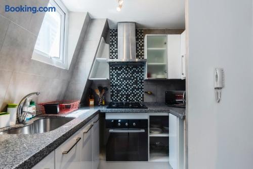 Cocina con mesón de piedra, lavaplatos y ventana con abundante luz natural