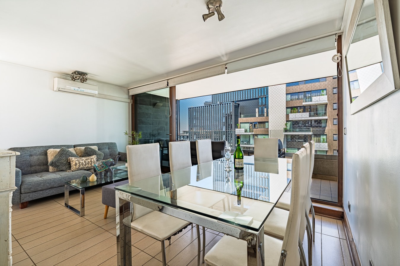 Comedor con mesa de vidrio para seis y living al fondo con ventanal