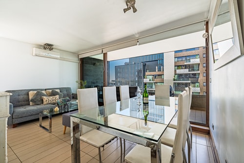Comedor con mesa de vidrio para seis y living al fondo con ventanal