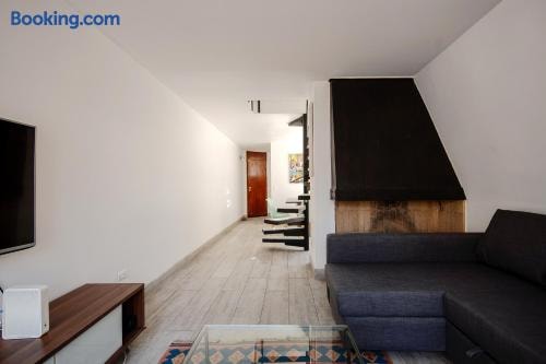 Pasillo del living con piso de madera, puertas de madera y sofá gris visible al fondo