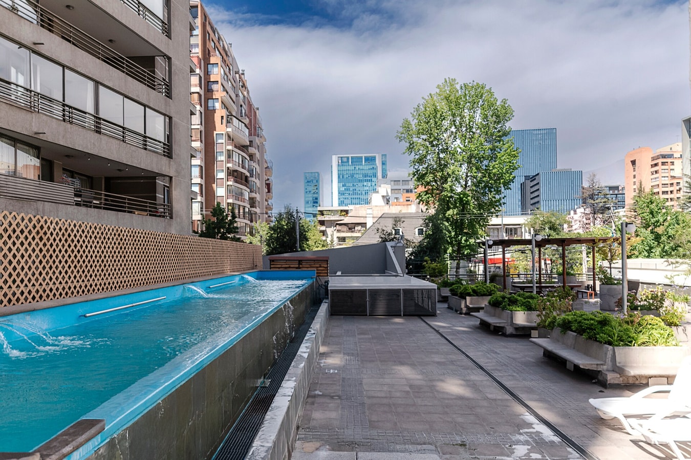 Piscina del edificio en azotea, tipo lap pool, con vista a edificios y terraza