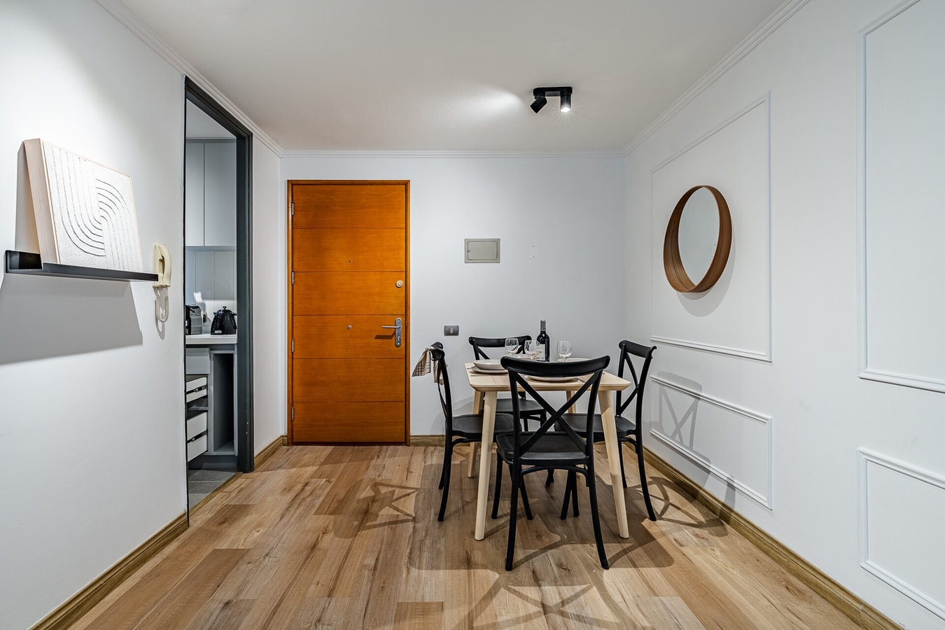 Comedor con mesa, sillas y puerta de acceso junto a espejo redondo