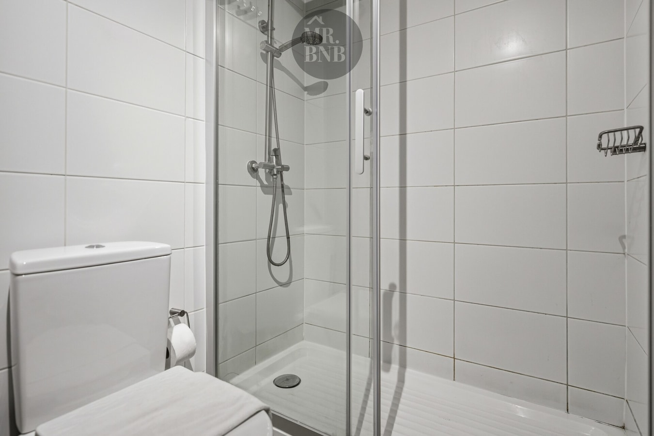 Baño con ducha de vidrio, inodoro y toallero