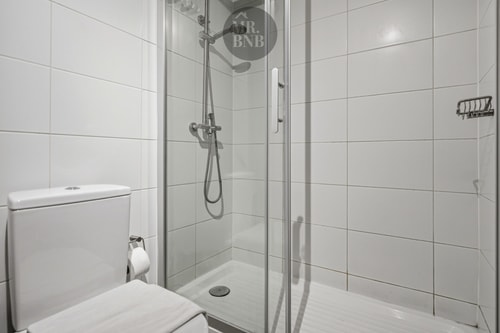 Baño con ducha de vidrio, inodoro y toallero