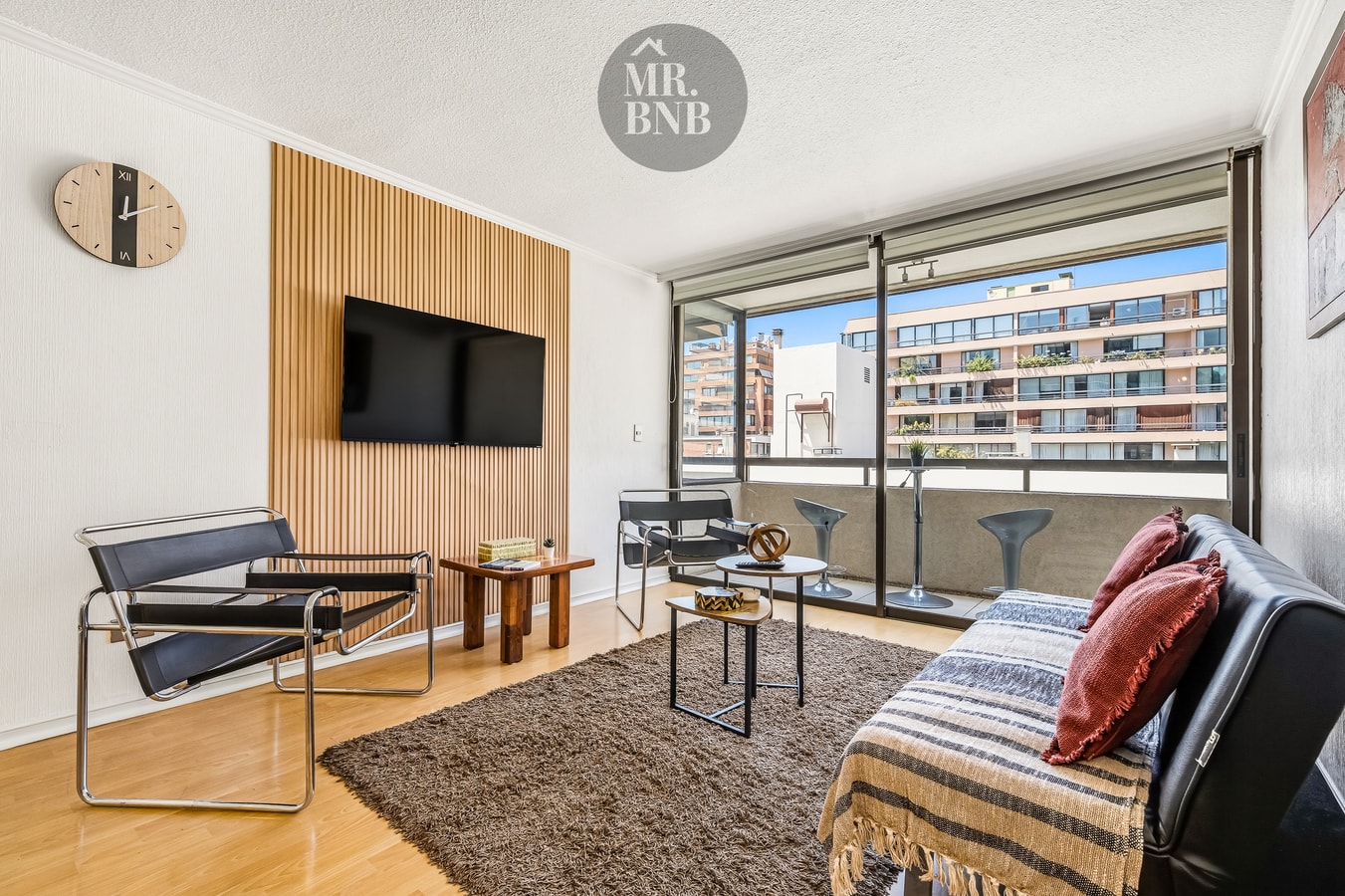 Living con sofá, televisor sobre panel de madera y ventanal corredizo hacia la terraza