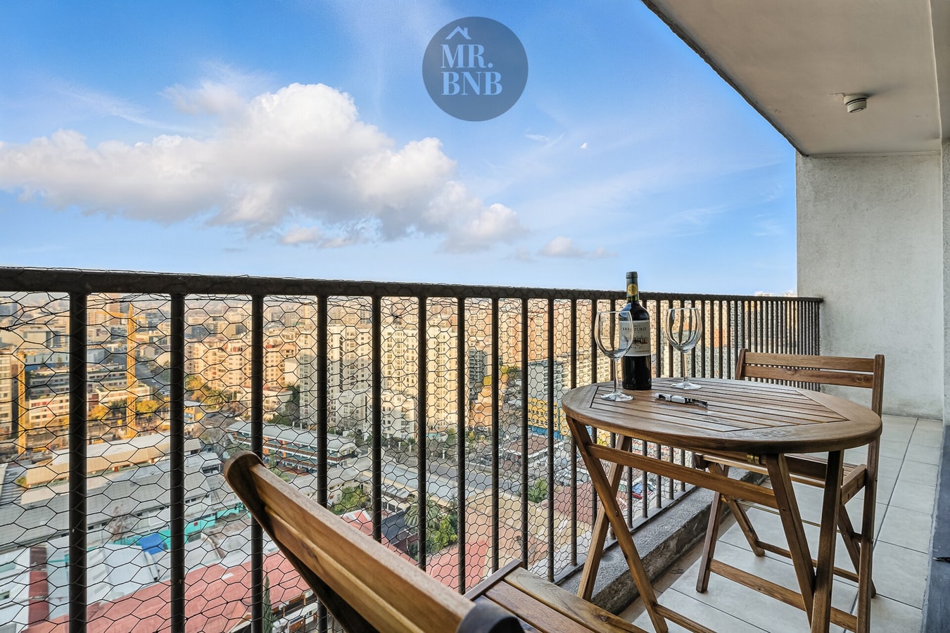 Balcón con mesa y sillas, vista panorámica de la ciudad y edificios