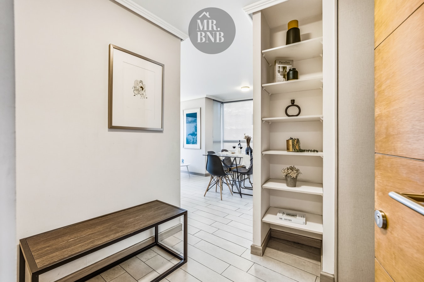 Pasillo con repisas decorativas, cuadro y comedor al fondo.