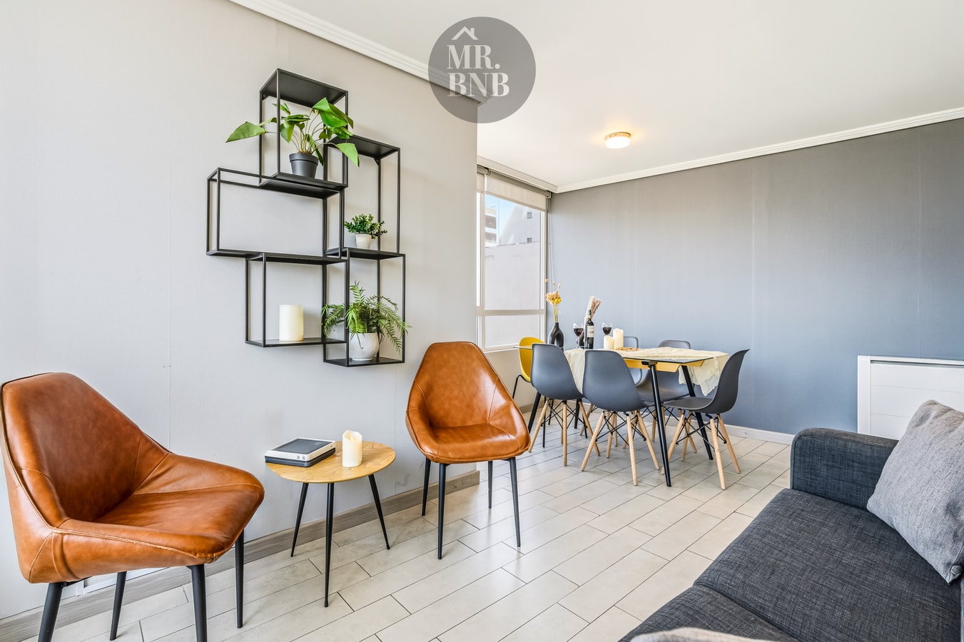 Living comedor con sillones de cuero, mesa redonda y repisas decorativas