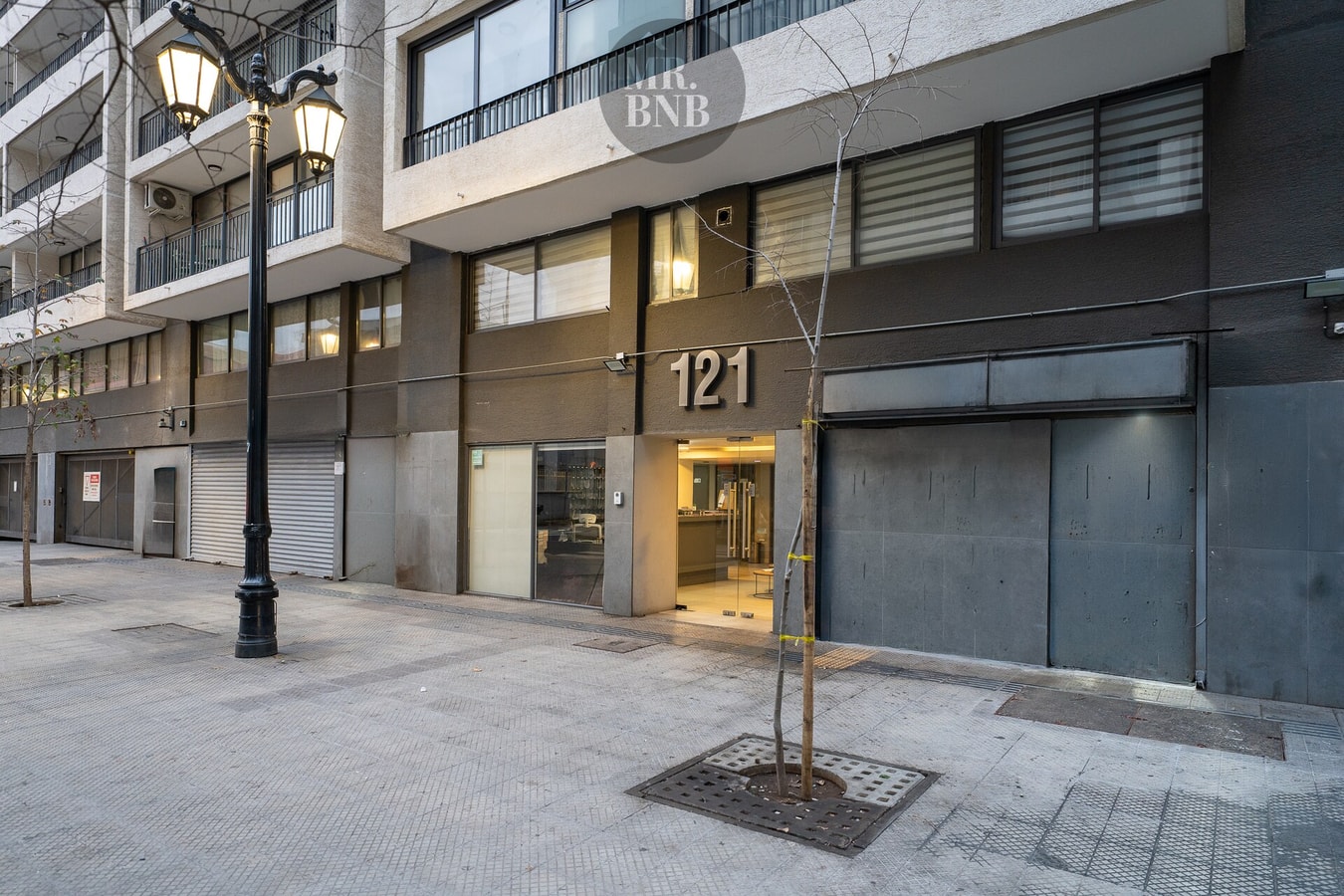 Fachada del edificio con acceso vehicular y calle empedrada, de noche