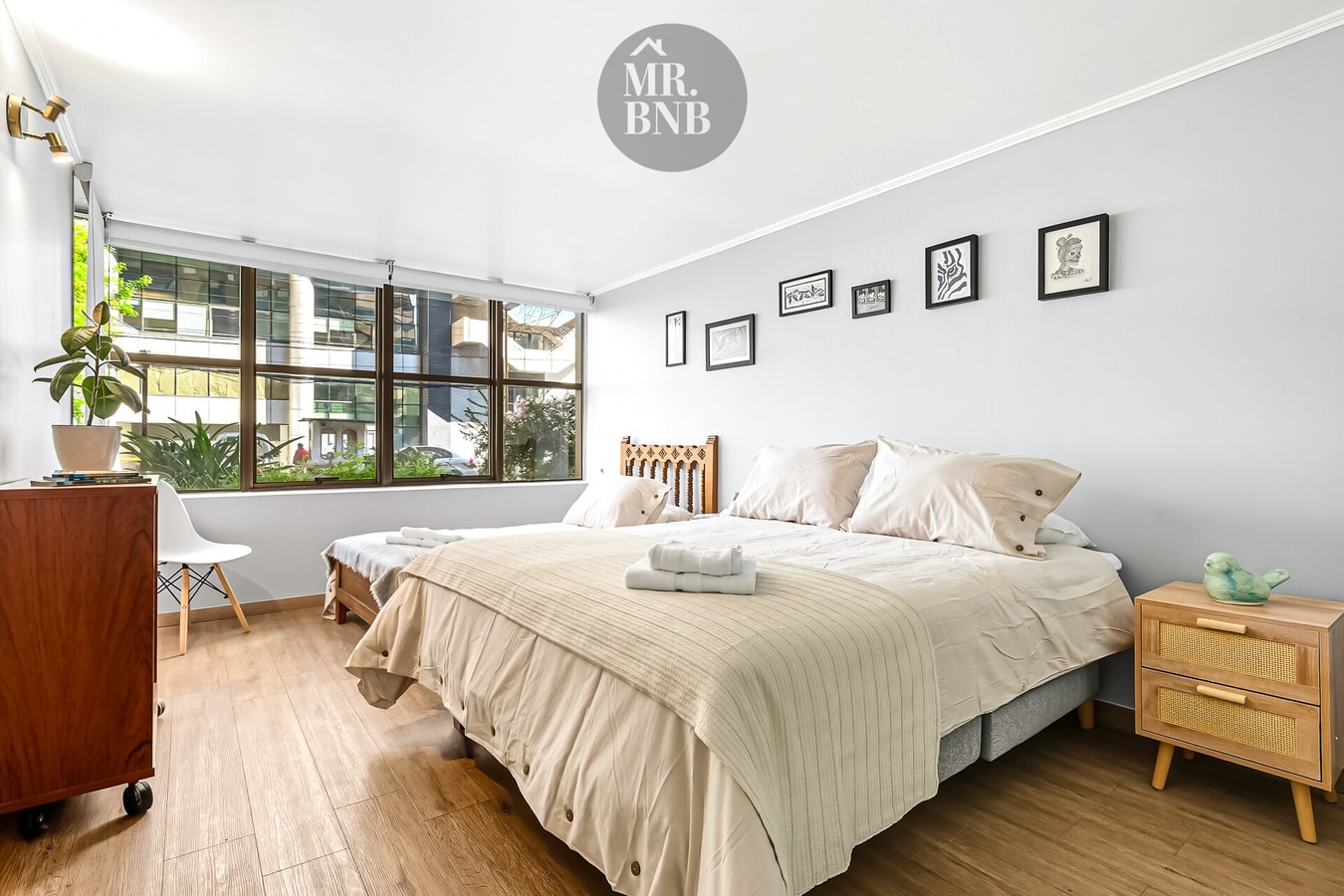 Dormitorio con cama de dos plazas, cuadro floral y luz natural