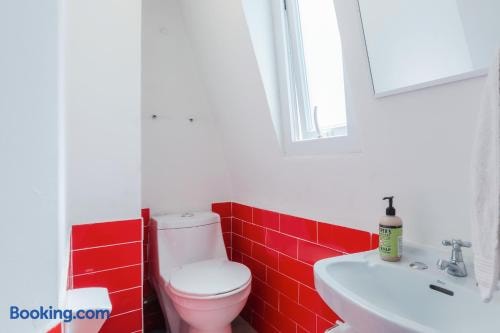 Baño con guardas de cerámica roja, inodoro, lavamanos y ventana con luz natural