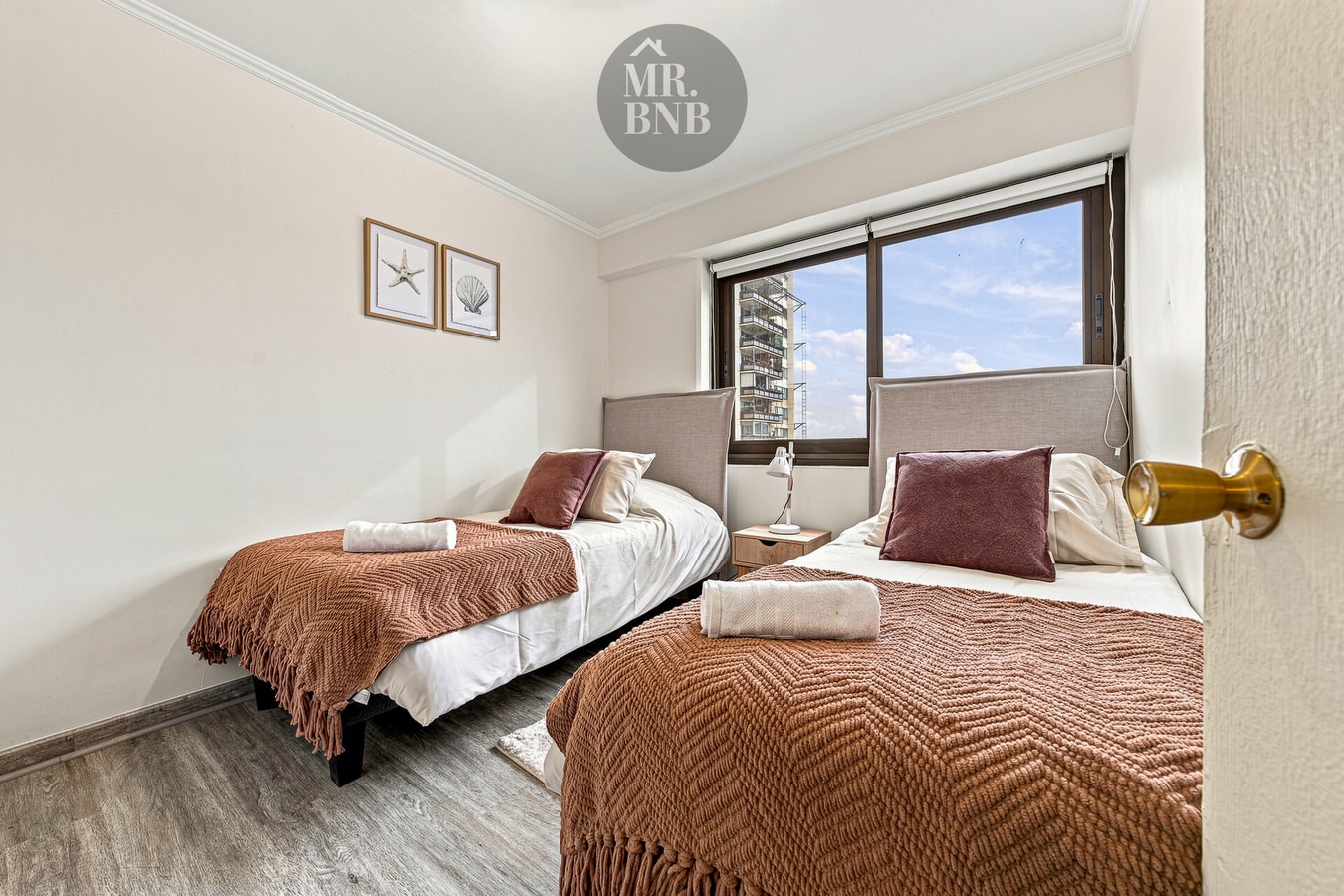 Dormitorio con cama de dos plazas y ventanal con vista a la ciudad.