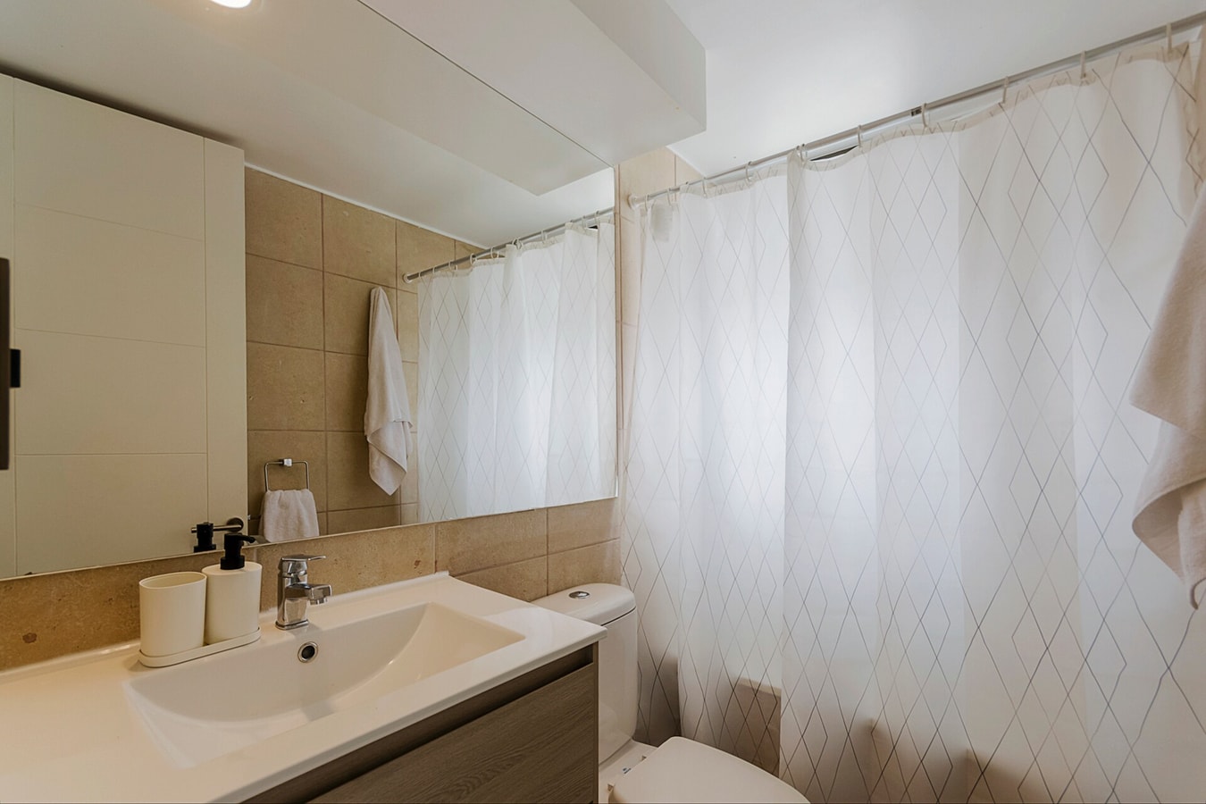 Baño con lavamanos, inodoro, cortina de baño y espejo