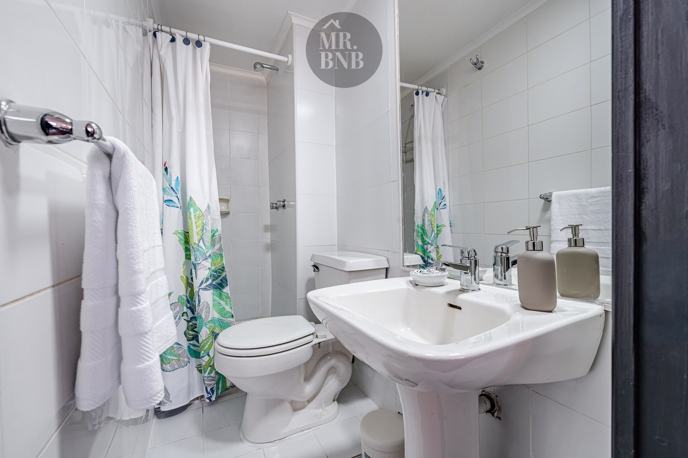Baño con inodoro, lavamanos de pedestal y cortina de ducha floral