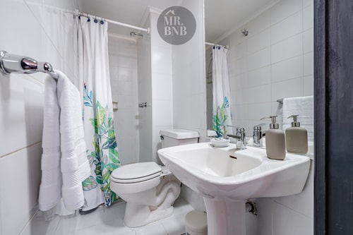 Baño con inodoro, lavamanos de pedestal y cortina de ducha floral