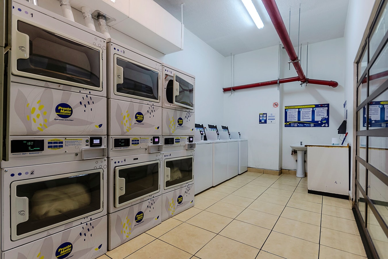 Lavandería del edificio con varias lavadoras y secadoras industriales