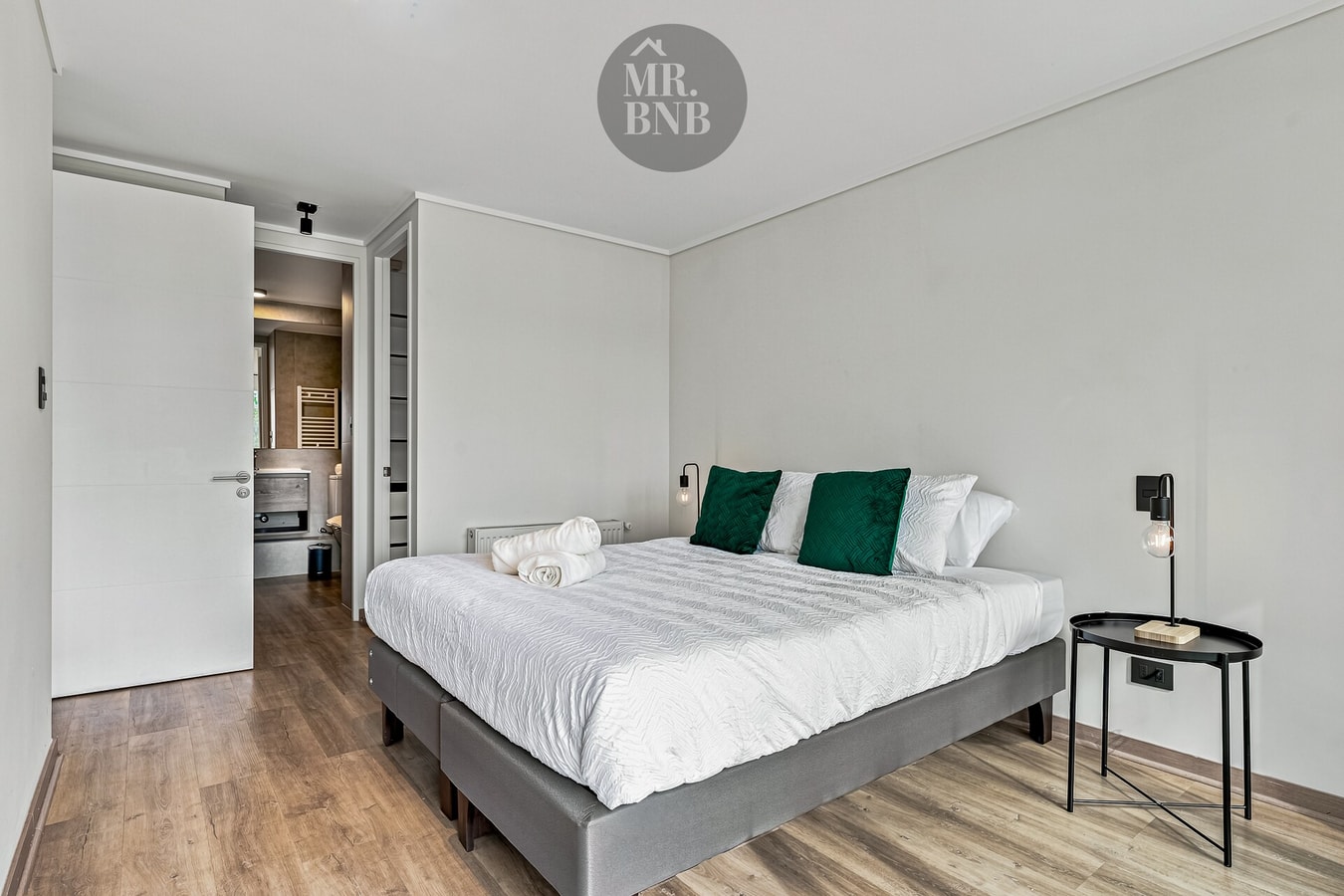 Dormitorio con cama de dos plazas, cojines verdes, velador y clóset corredizo